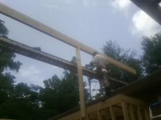 Carpenter setting a ridge beam over a new addition frame — Ice Dam Removal by Roofing Brothers in Lineville