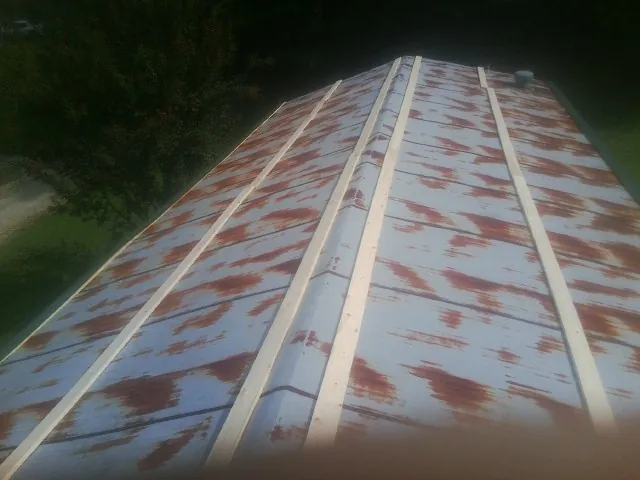 Rusted metal roof panels with new wood purlins before replacement — Storm Damage Roof Repair in Lineville by Roofing Brothers