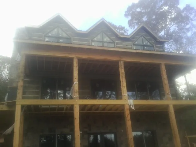 Dormers and porch framing on a large log home under construction — Roof Coating work by our crew in Lineville