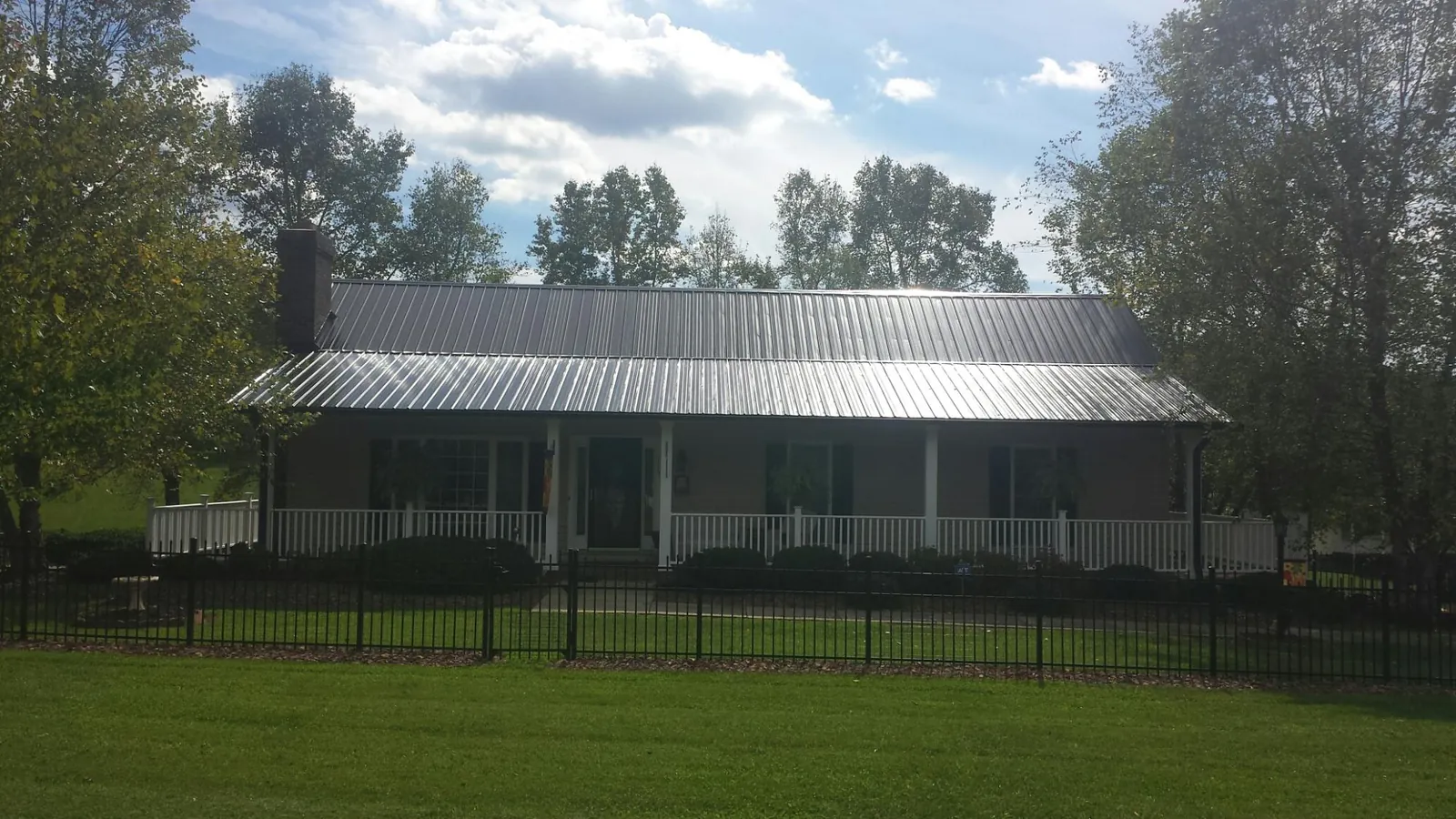 Gray metal roof on a brick ranch with a full width front porch — Gutter Guard Installation work by our crew in Lineville