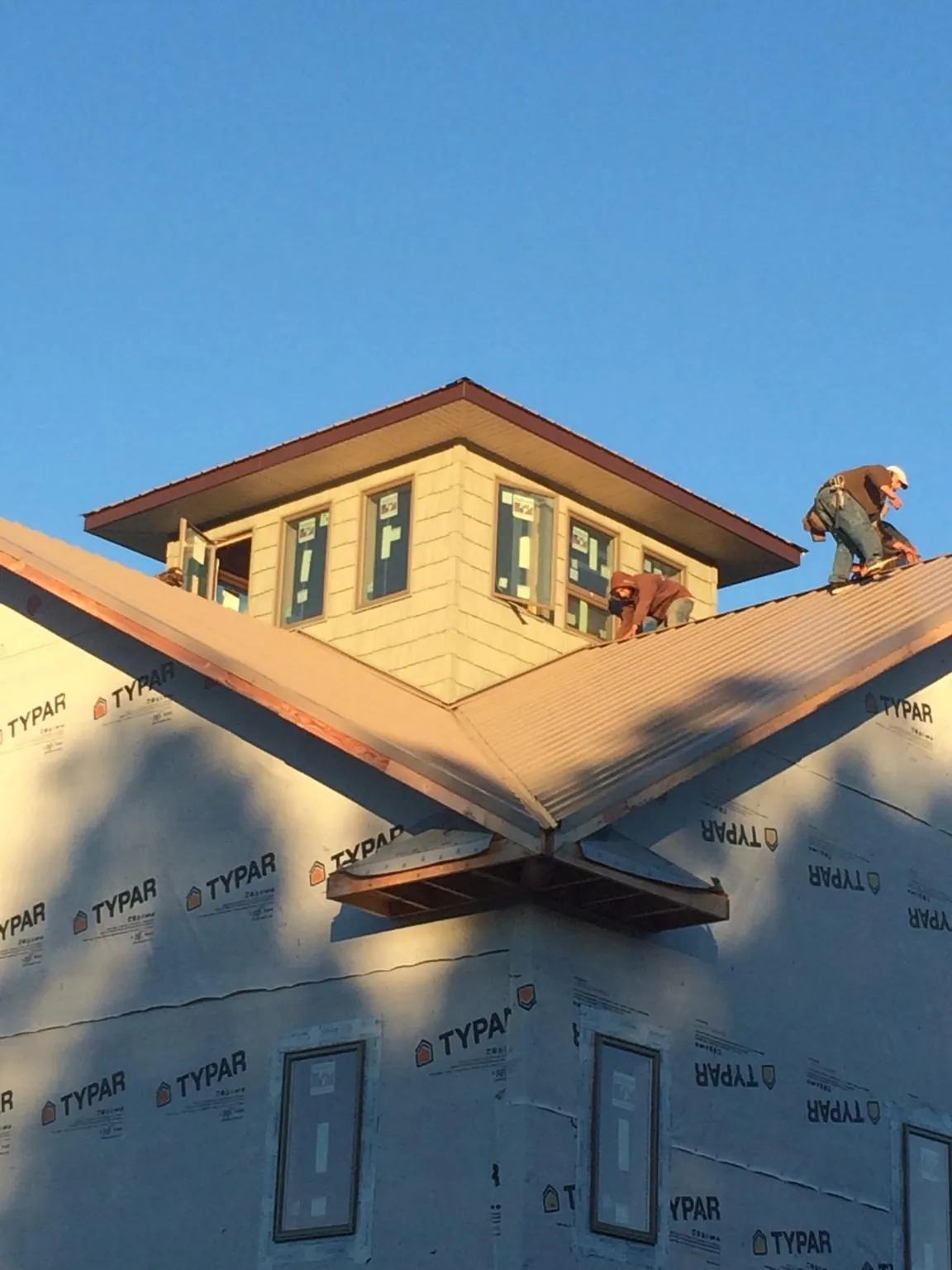 Roofers working around a rooftop cupola on a new metal roof at sunset — Roof Waterproofing in Lineville by Roofing Brothers